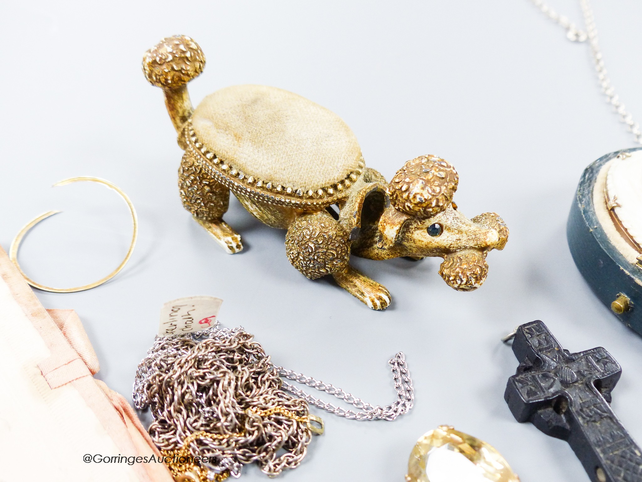 A small group of assorted bijouterie including base metal and composite poodle pin cushion, a white metal and enamel locket on sterling chain, a citrine brooch(lacking pin), a slit pearl set yellow metal mourning clasp e